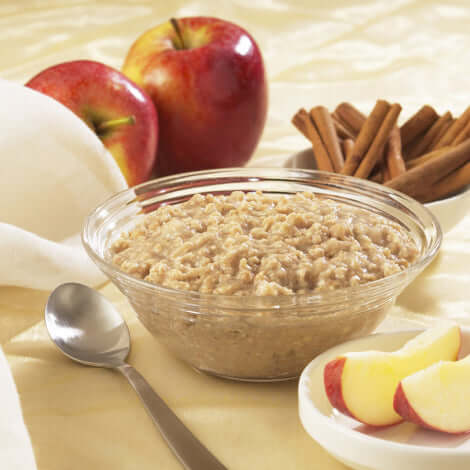 Delicious protein oatmeal served in a bowl, surrounded by apples and cinnamon sticks, ideal for a healthy breakfast.